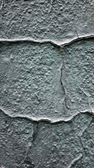 A textured surface of an old, cracked wall with uneven paint and distinctive fracture lines. Highly detailed gray texture.