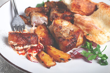 A plate with the remains of a pork kebab, there are no people.