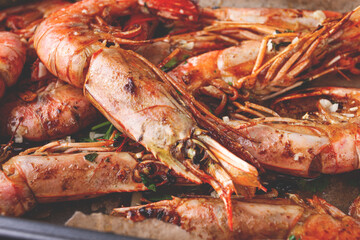 Juicy grilled shrimp, placed on a baking sheet lined with parchment paper, garnished with herbs and lemon.
