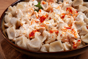 Traditional Turkish dumplings served with yogurt and spicy sauce on a green decorative plate