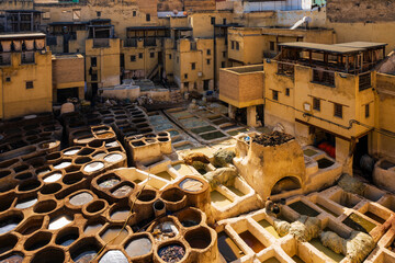 Traditional outdoor tannery with numerous circular pits for leather processing in a historic setting. Fez, Fez-Meknes, Northern Inland Morocco