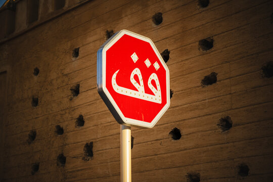 Red octagonal stop sign with Arabic text against a textured wall. Fez, Fez-Meknes, Northern Inland Morocco