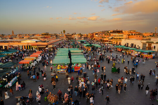 Vibrant marketplace bustling with people and colorful stalls at sunset. Marrakesh, Morocco