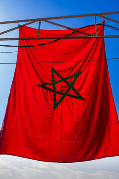 Red flag with green star hangs under clear blue sky. Marrakesh, Morocco