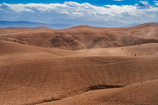 Expansive desert landscape with rolling sand dunes under a bright blue sky with scattered clouds. Agafay Desert, Marrakesh-Safi, Morocco