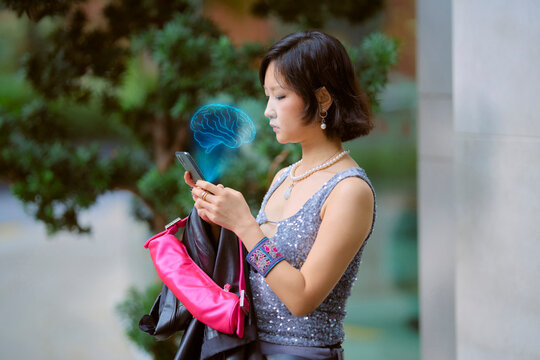 Woman using smartphone with holographic brain illustration near trees. Shanghai, China