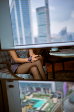 Woman in fashionable dress using a phone in modern high-rise city setting. Shanghai, China 