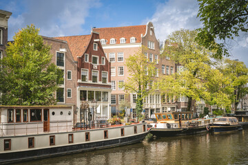 Historic canal houses and boats under a partly cloudy sky in Amsterdam. Amsterdam,. Netherlands