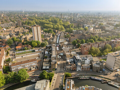 Aerial view of a cityscape with green parks and residential buildings under a clear sky. London, UK