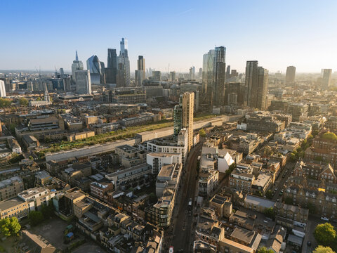 Aerial view of a sprawling urban landscape with modern skyscrapers under a clear blue sky. London, UK