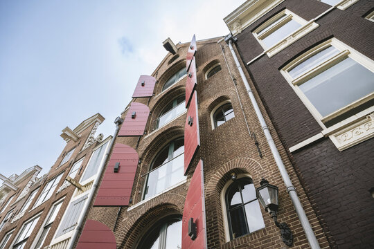 Tall brick buildings with decorative pink shutters against a blue sky. Amsterdam,. Netherlands