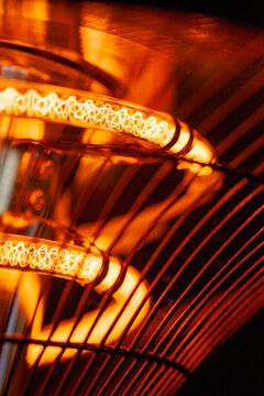 Close-up of glowing orange heating element with wire cage design.