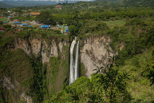 Majestic waterfall cascading down a lush green cliff amidst a verdant landscape. San Agustin, Colombia