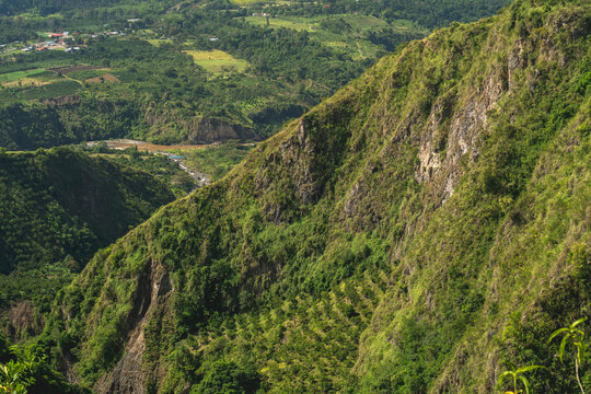 Lush green mountainside with terraced vegetation and a valley in the background. San Agustin, Colombia