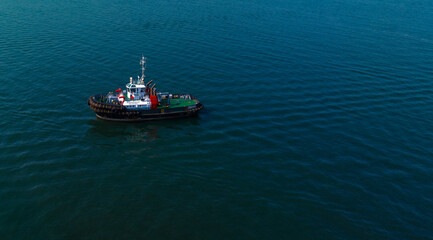 A solitary tugboat navigates calm, deep blue ocean waters beneath a clear sky.  Cartagena, Colombia