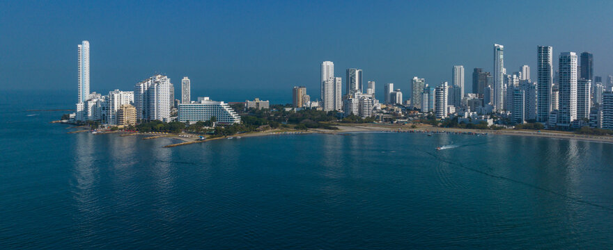 Panoramic view of a coastal city skyline with tall modern buildings reflecting in the calm sea. Cartagena, Colombia