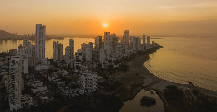Coastal city skyline at sunset with tall buildings and a serene beach. Cartagena, Colombia