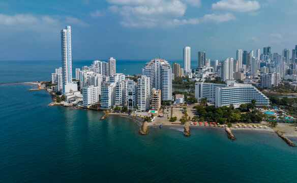 Aerial view of a coastal cityscape with high-rise buildings and a clear blue ocean. Cartagena, Colombia - Powered by Adobe