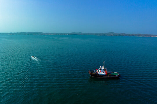 Tugboat and small speedboat navigate vast blue ocean under clear sky. Cartagena, Colombia