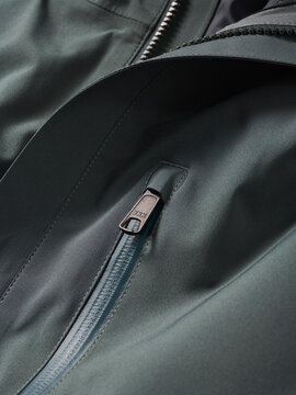 Close-up of a blue-gray jacket with a zipper pocket and metal pull tab.