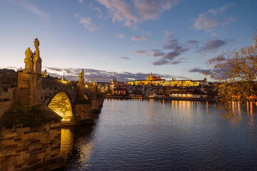 Castle of Prague and Charles bridge reflected on Vltava river at sunset