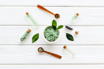Obraz na płótnie Canvas Organic cosmetics products - tea tree essential oil and sea salt near green leaves top view