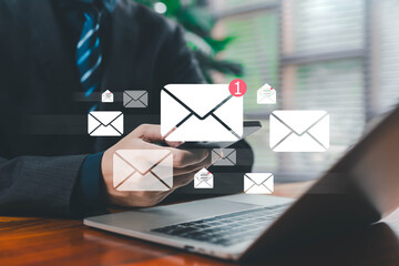 Business person checking email notifications on a smartphone while working on a laptop, representing digital communication, mobile inbox management, online messaging, workflow efficiency, and modern