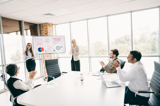 Business team applauding during a presentation in a bright office setting showcasing teamwork and professional collaboration