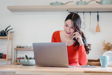 Young woman laptop phone smiling at home kitchen workspace relaxed and focused energetic
