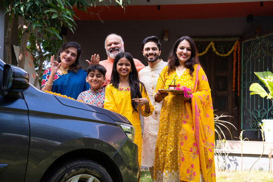 Indian family performing car puja ceremony to welcome their new vehicle with blessings