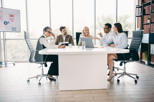 Group discussion in a modern office setting with a diverse team collaborating on a business project