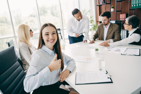 Confident businesswoman showing enthusiasm during a collaborative team meeting in a modern, bright office space - Powered by Adobe
