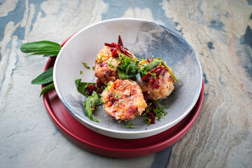 Homemade vegan bread knodel dumpling with beetroot and fresh buttered sage served as close-up on a design plate
