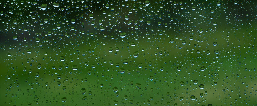 A rainy day window view. Rain drops on window. Condensed rain drop on the car glass window on a rainy day. Dew moisture condensation on wet mirror background. Fresh weather. Water raindrop bg