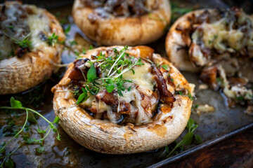 Portabello mushrooms stuffed with cheese and fresh herbs, oven baked with raclette cheese served as close-up on a backing form
