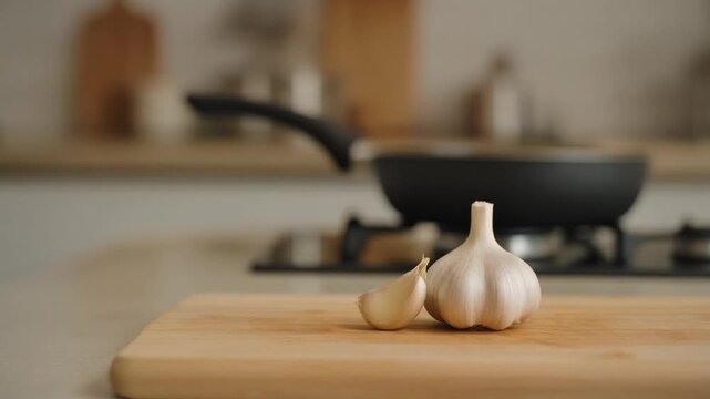 Fresh garlic cloves on a wooden cutting board, with a blurred kitchen background