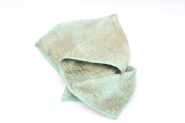 Close-up of a dirty, worn, and stained light blue, mint microfiber cleaning cloth or rag, folded on a white background. Concept for cleaning, housework, laundry, and dirt. Used textile texture.