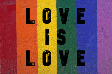 love is love. words painted on a wall in the colors of the rainbow flag
