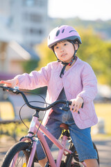 ピンクの自転車に乗る日本の女の子と明るい公園の屋外風景