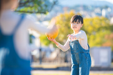 公園でドッジボールをして遊ぶ元気な女の子