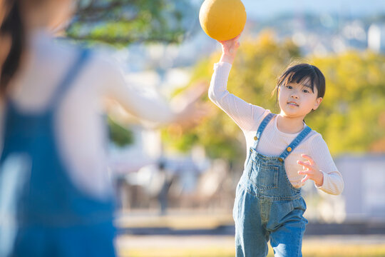 公園でドッジボールをして遊ぶ元気な女の子がボールを投げる瞬間
