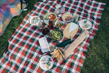 Picnic blanket with various foods and drinks outdoors