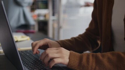 Rack focus of young female manager doing report on wireless laptop while Asian colleagues analyzing financial presentation in background at office - Powered by Adobe