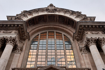 A majestic arched window of the Brussels Stock Exchange building, reflecting the light of the interior architecture, with decorative columns and a detailed cornice.