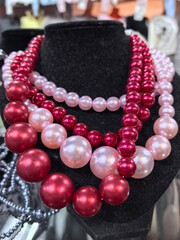 Elegant display of vibrant red and pink pearl necklaces at a market stall