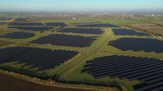Aerial view of rows of solar panels on a green field, creating a geometric pattern against the landscape, Newmarket, England, United Kingdom.