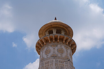 Ornate historical minaret with floral carvings beneath a partly cloudy sky