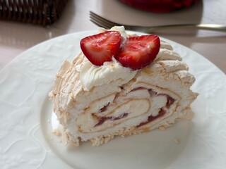 Strawberry meringue roll cake dessert with cream on white plate  