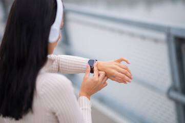 Woman with headphones checking smartwatch data