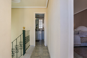 Upstairs hallway with wrought iron railing and access to bathroom and bedroom